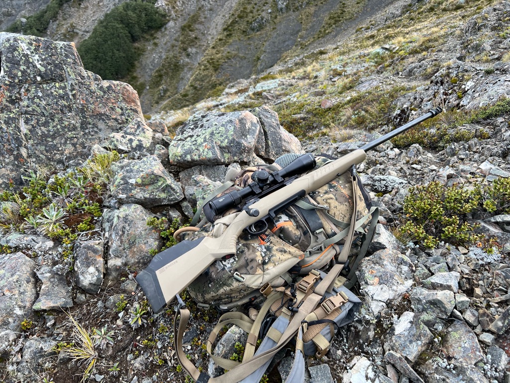 Savage 110 Tactical rifle resting on hunting pack in mountain terrain during Mediate Expeditions safari.
