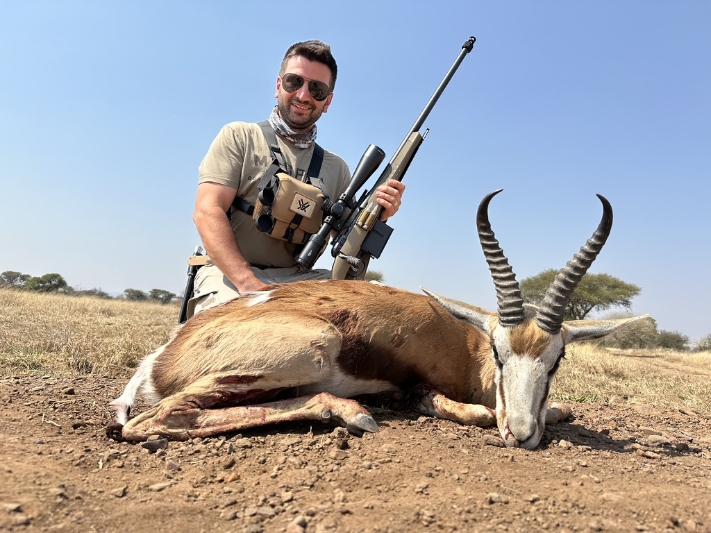 Hunter with rifle and trophy springbok antelope on South African plains – Mediate Expeditions safari hunt